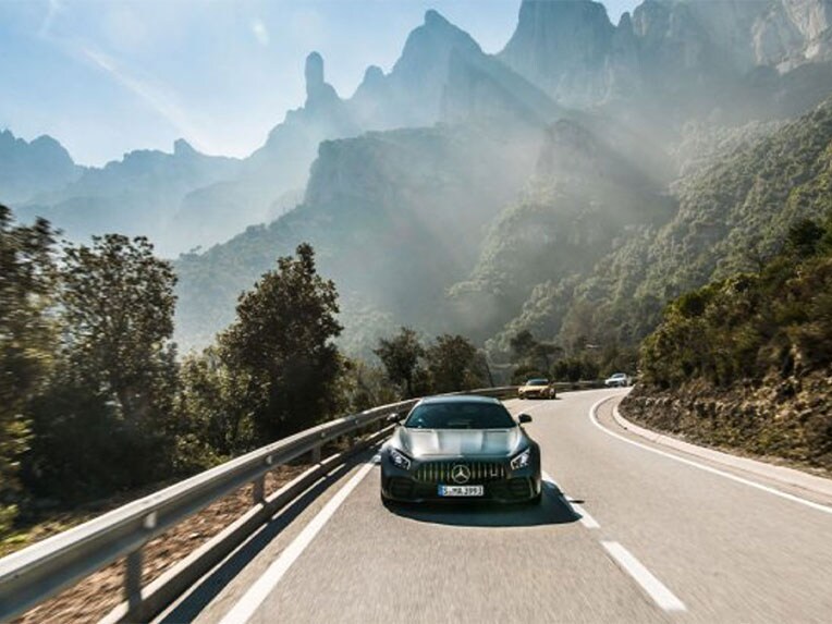 Front view of a Mercedes-AMG vehicle driving on a country road.